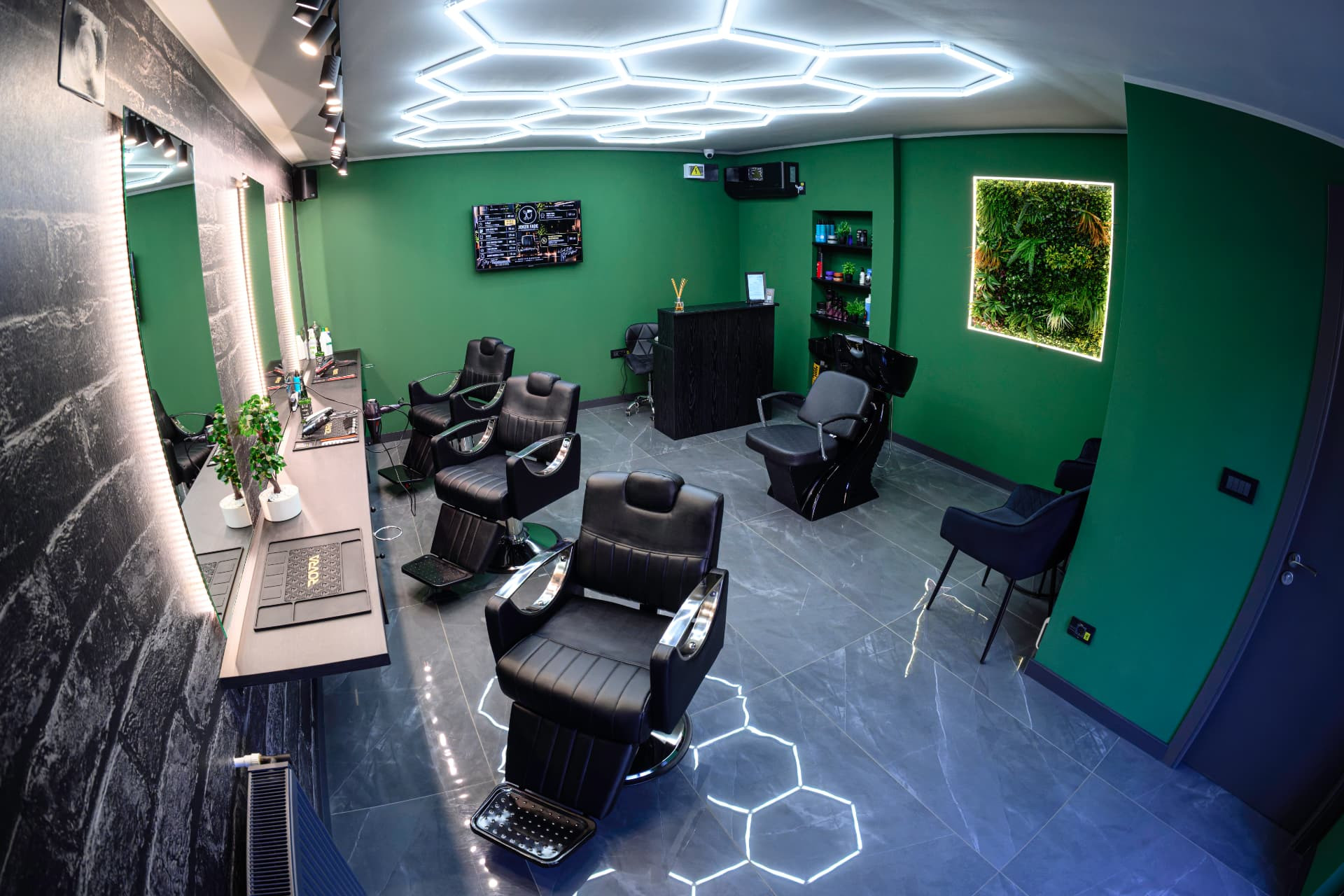 Salonul Joker Fade Barbershop cu scaune negre, pereți verzi și lumini hexagonale